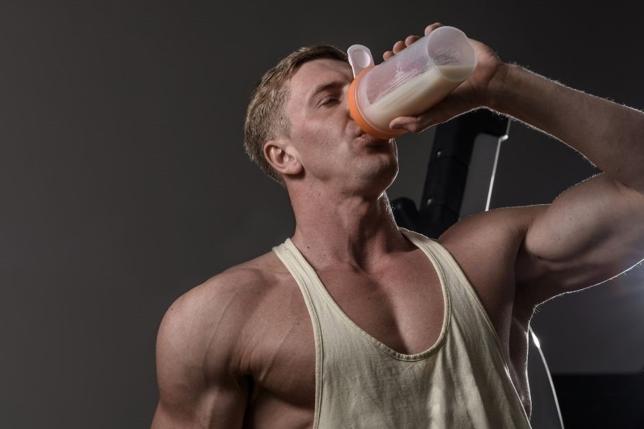 Eiweiß dargestellt von Bodybuilder mit Shake