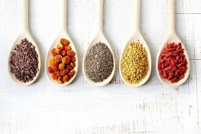 Abnehmen mit Superfoods dargestellt von 5 Löffeln mit gesunden Samen und Nüssen