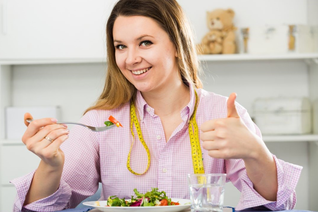 Frau mit Teller und Maßband symbolisiert besten Weg zum Abnehmen