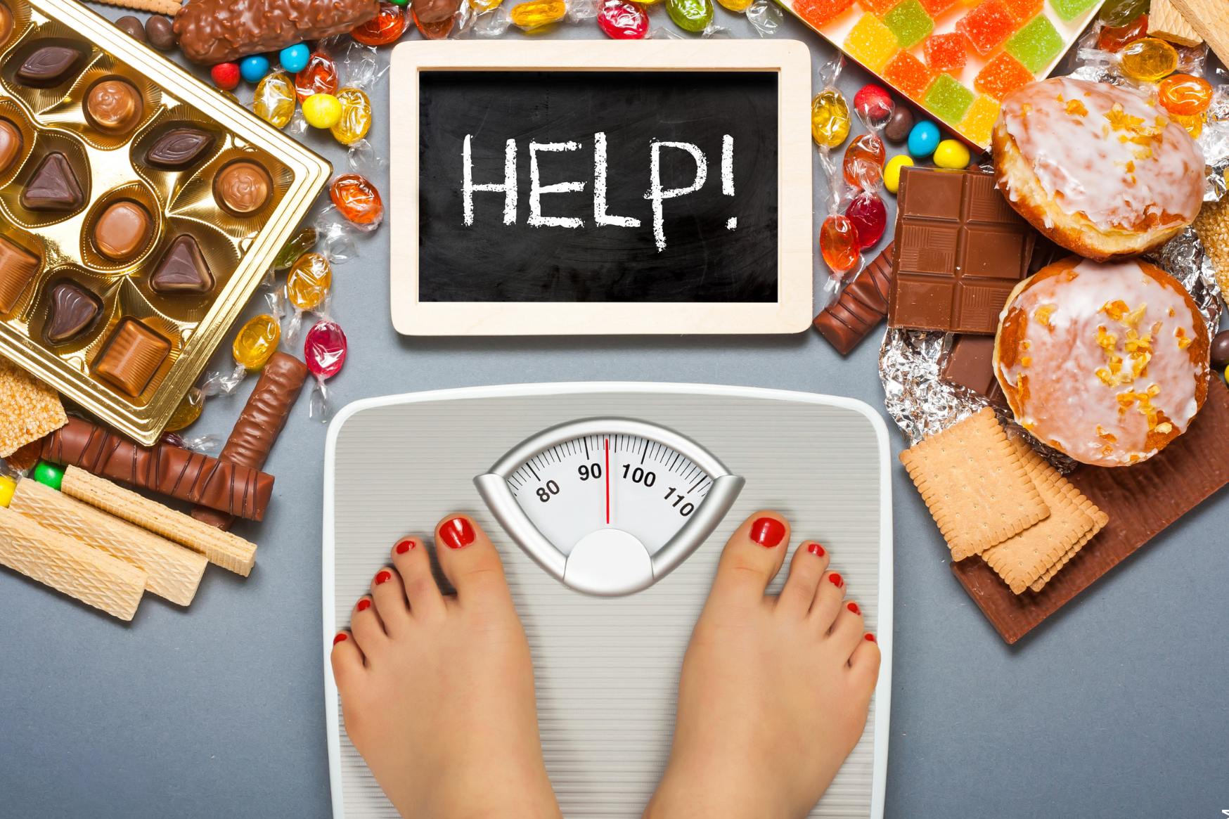 Diät Programm symbolisiert durch Waage und viele Süßigkeiten herum