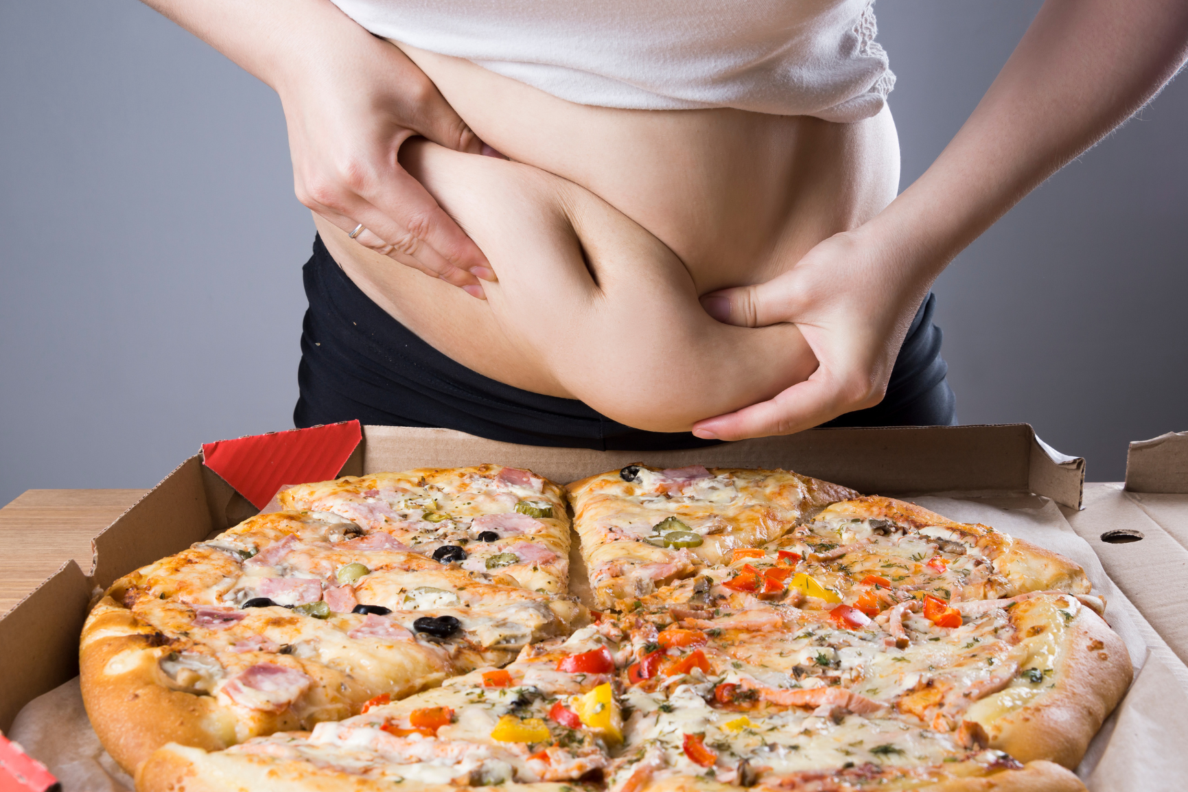 Fettverbrennung dargestellt von übergewichtigem Frauenbauch mit Pizza