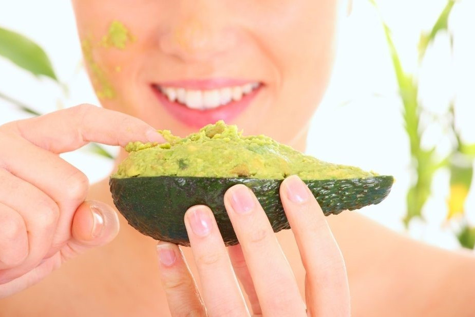 Abnehmen mit Avocado dargestellt von Frau mit halber Avocadofrucht