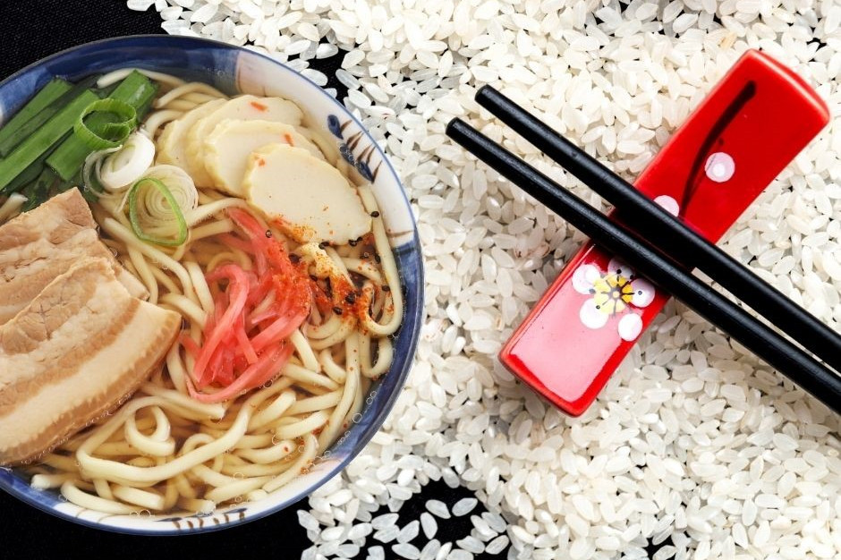 Okinawa-Diät dargestellt von Reiskörnern, traditionellem japanischen Gericht und Stäbchen